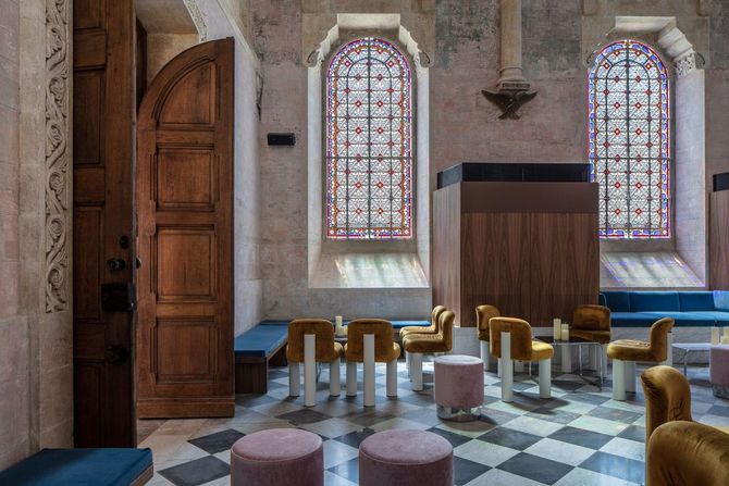 A room with tables and chairs and stained glass windows.