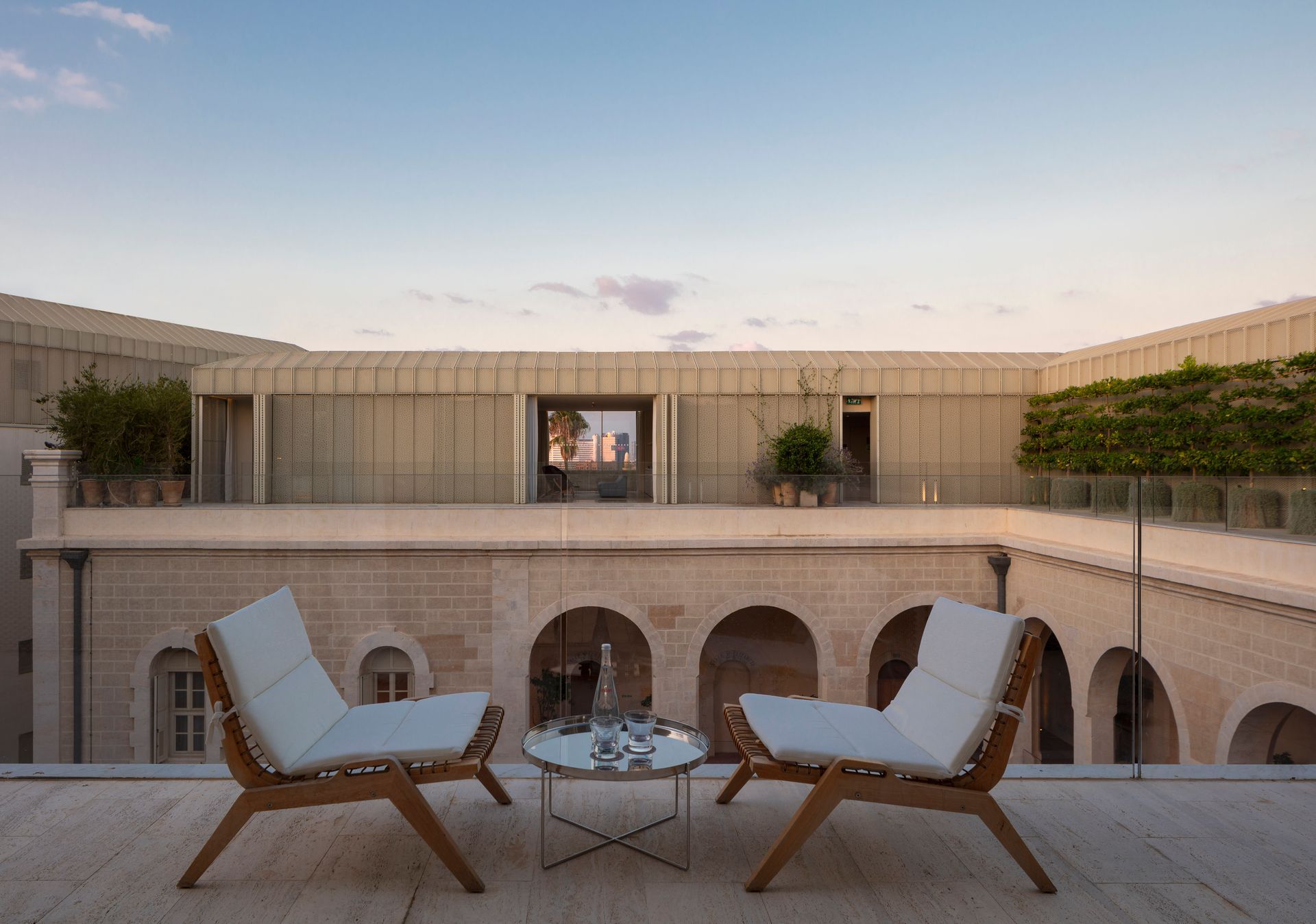 There are two chairs and a table on the balcony.