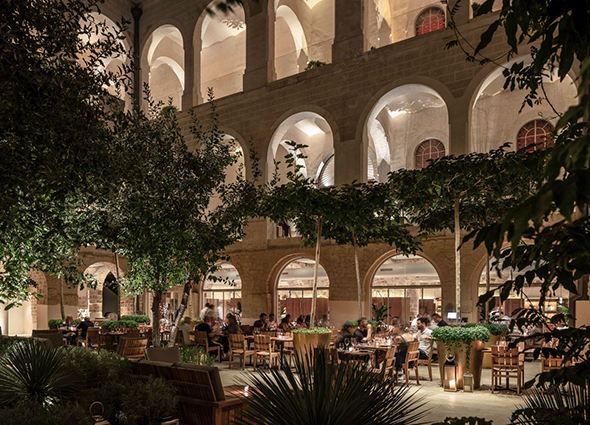 A group of people are sitting at tables outside of a building at night