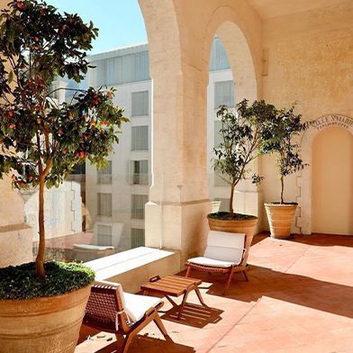 A balcony with chairs and trees in pots