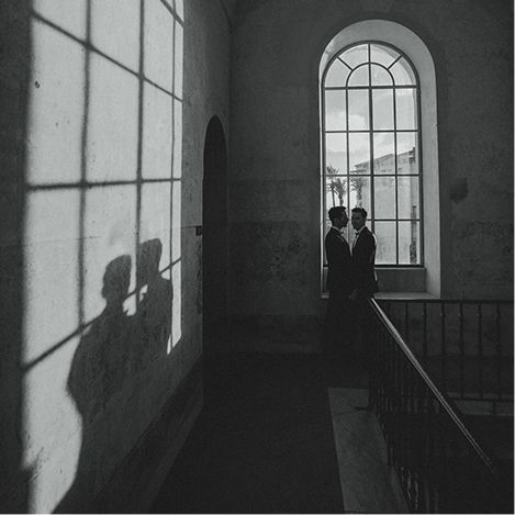A black and white photo of a couple standing in front of a window.