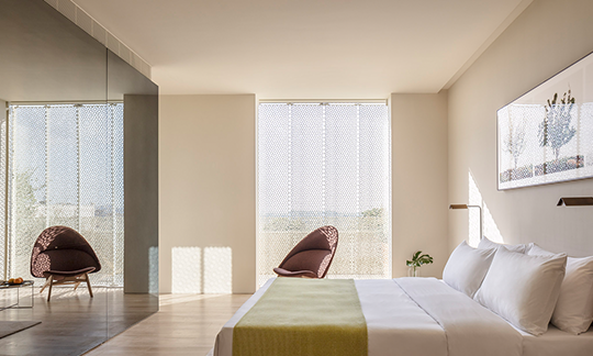 A bedroom with a bed , chairs and a large window.