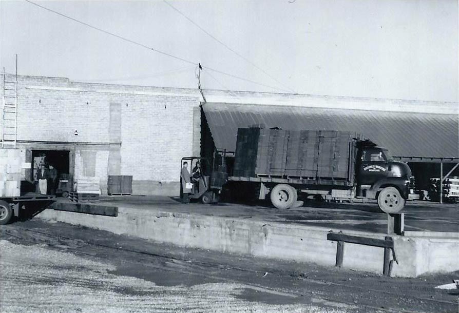 A black and white photo of a truck in front of a building