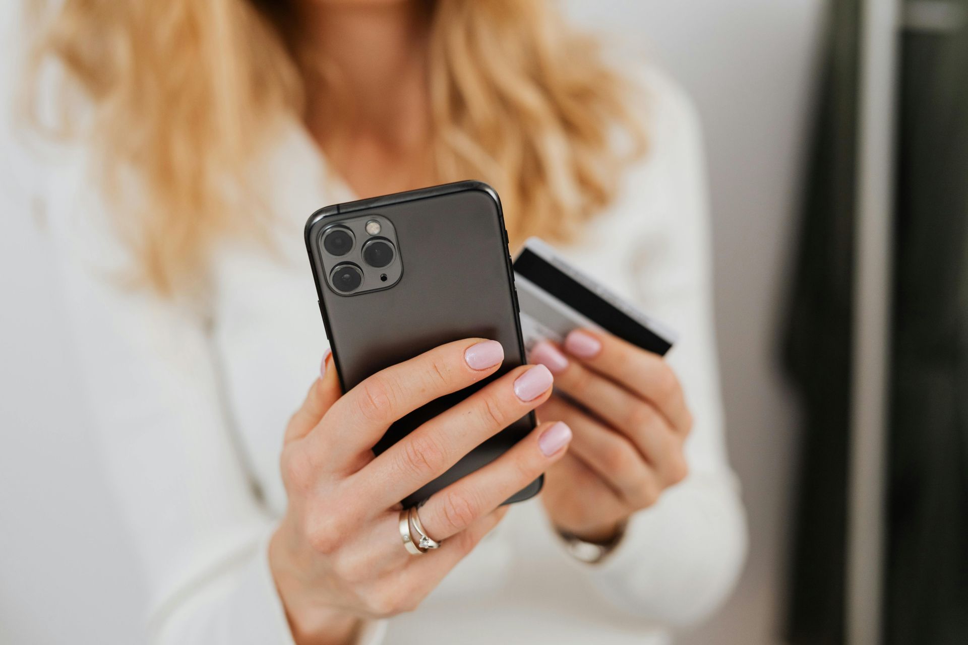 Uma mulher está segurando um cartão de crédito e um celular.