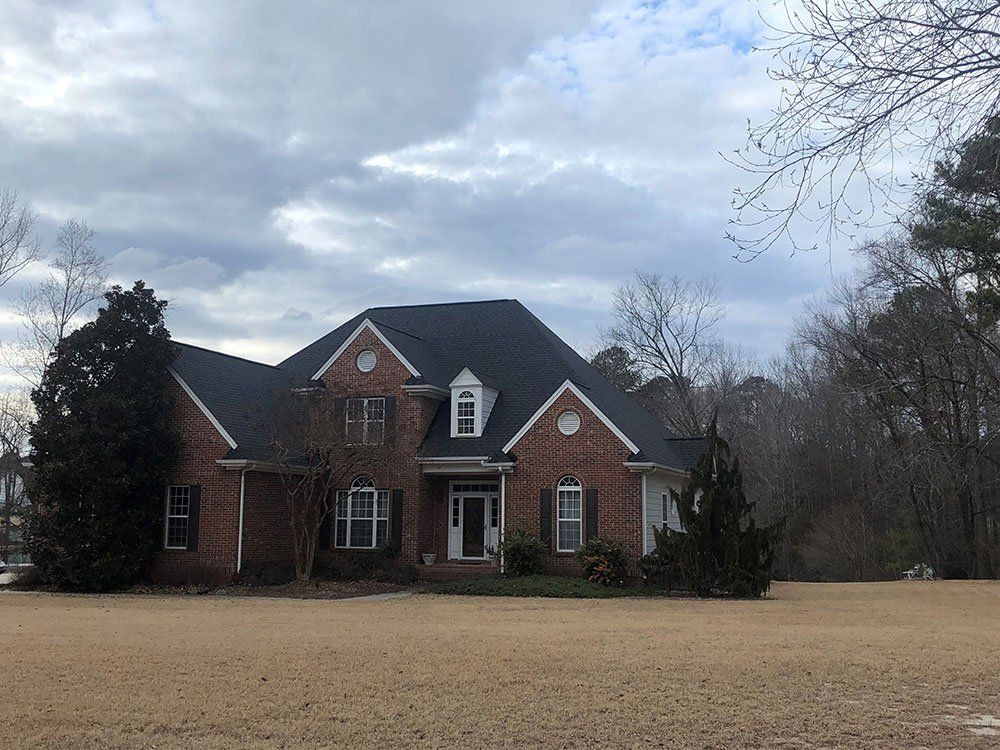 red brick farm house after roof replacement from Shield Roofing
