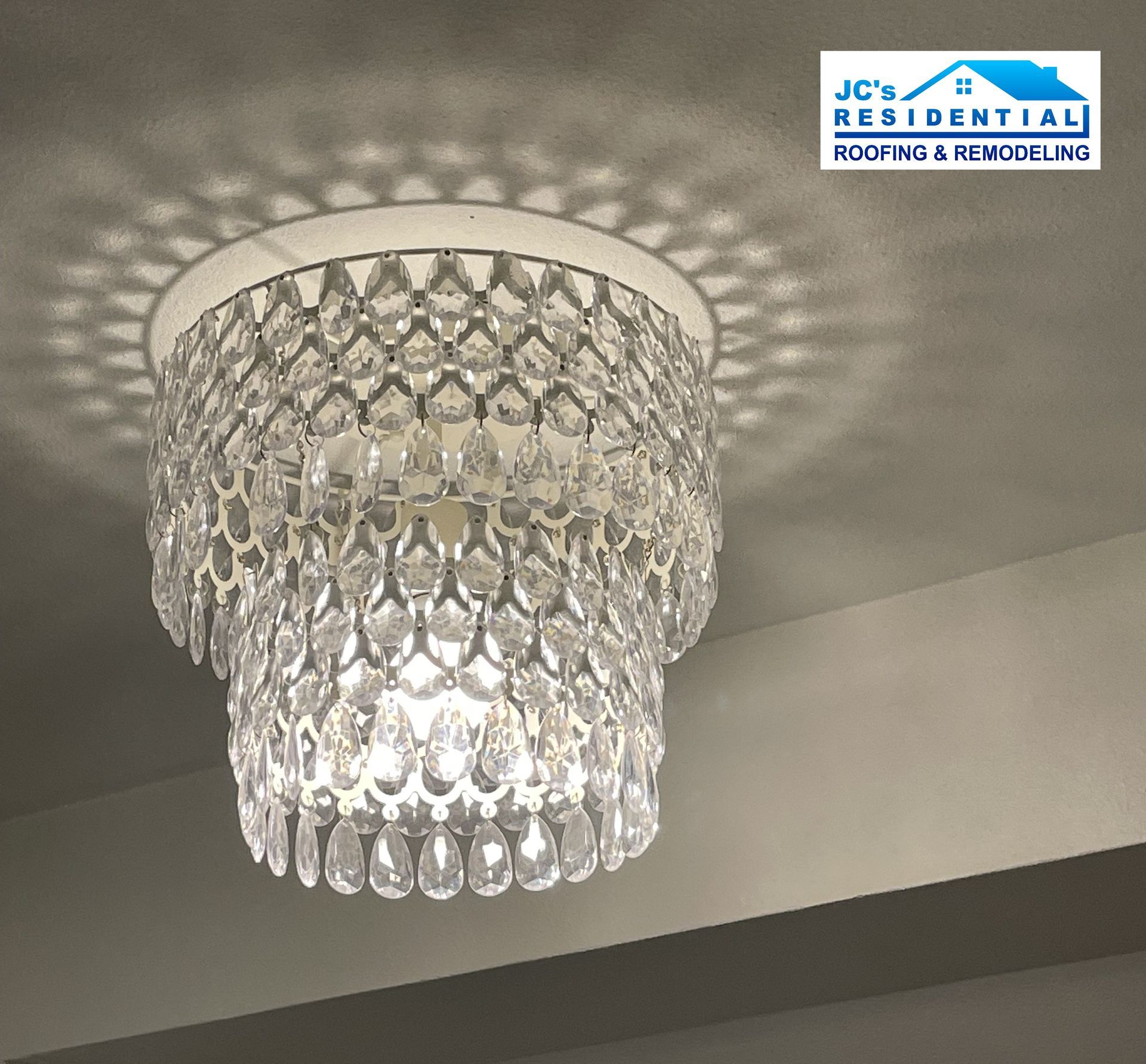 Crystal chandelier hanging from a white ceiling, casting patterned shadows.