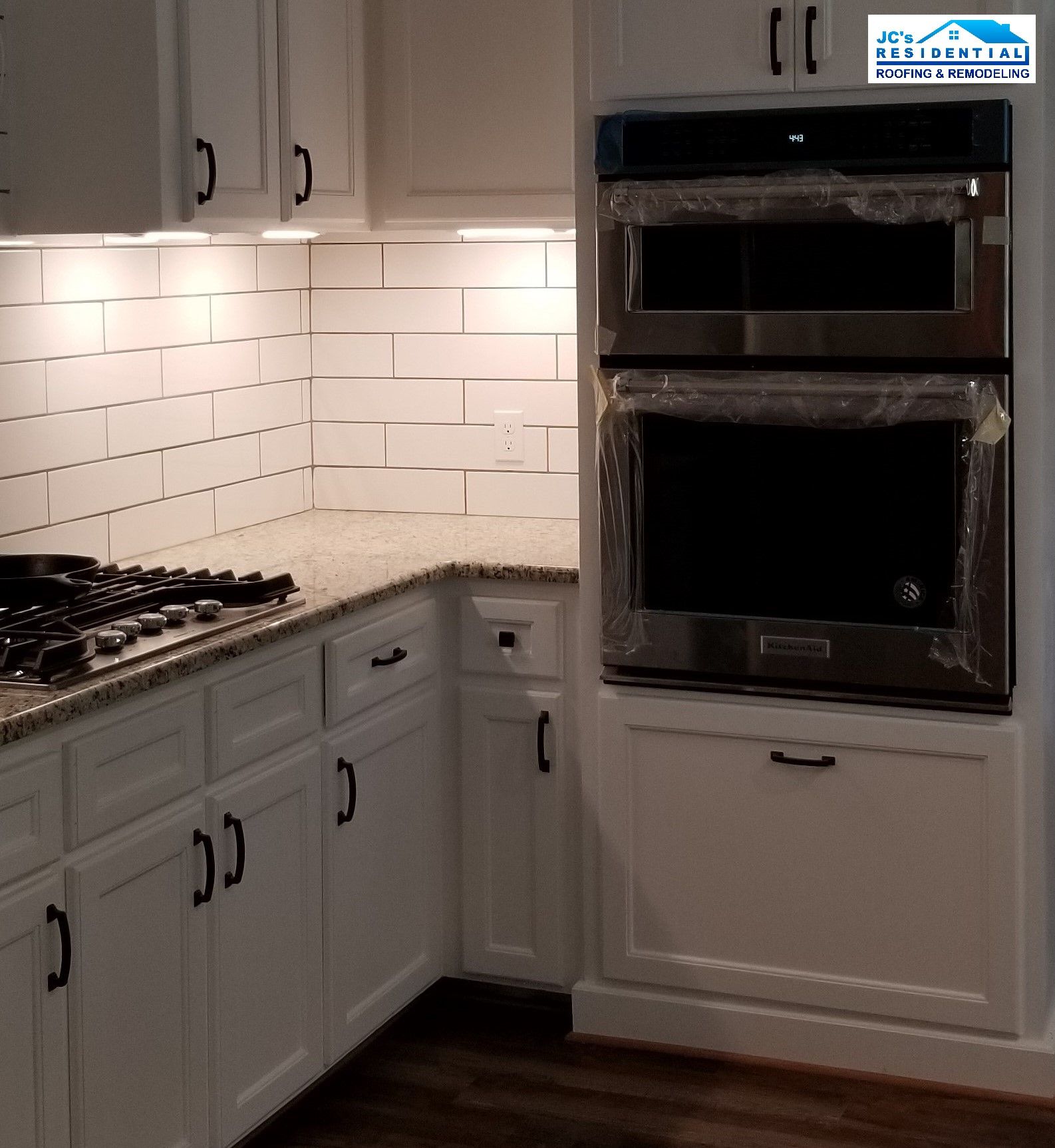White kitchen with stainless steel oven, white cabinets, and gas stovetop.