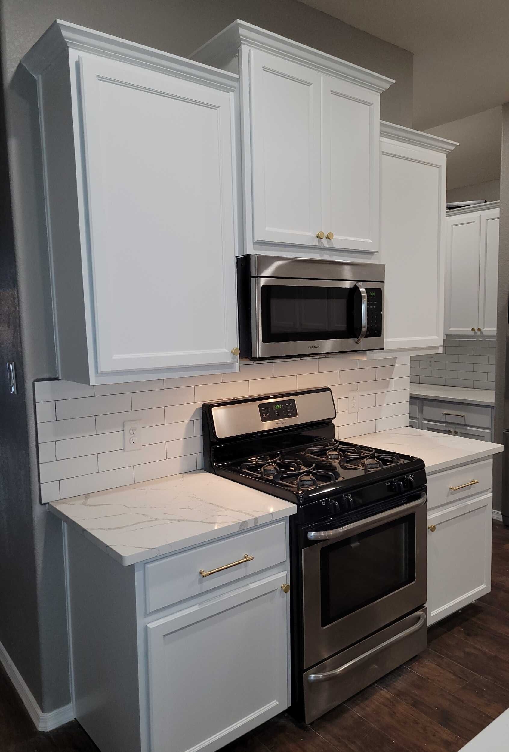 White kitchen cabinets with a stainless steel range and microwave.