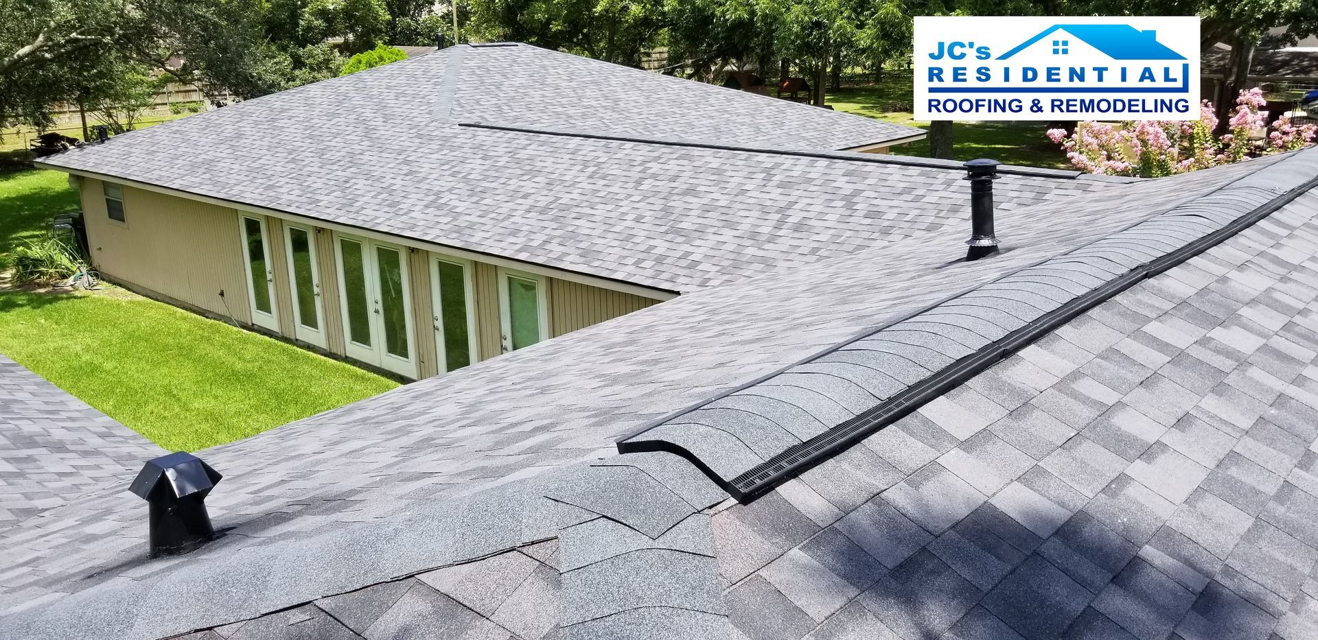 A gray shingled roof with a chimney and vent.