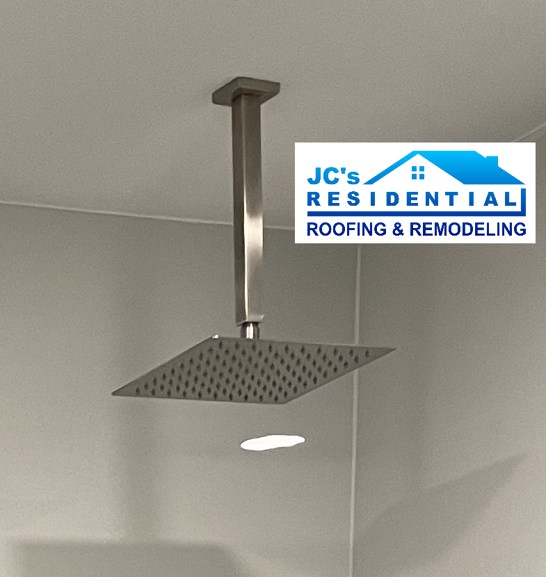 Square showerhead fixture suspended from ceiling in a bathroom.