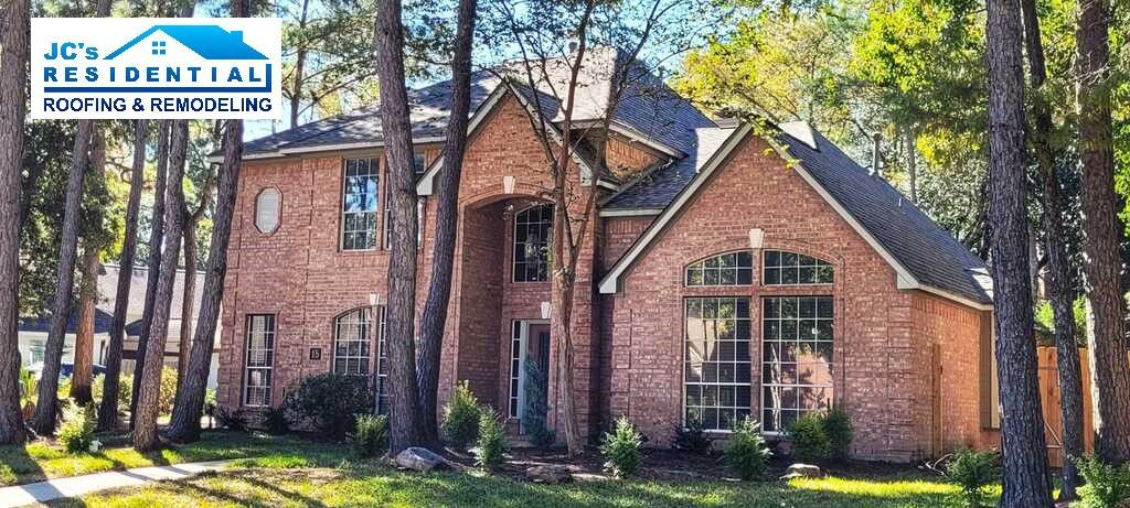 Brick house with tall windows and trees in front.