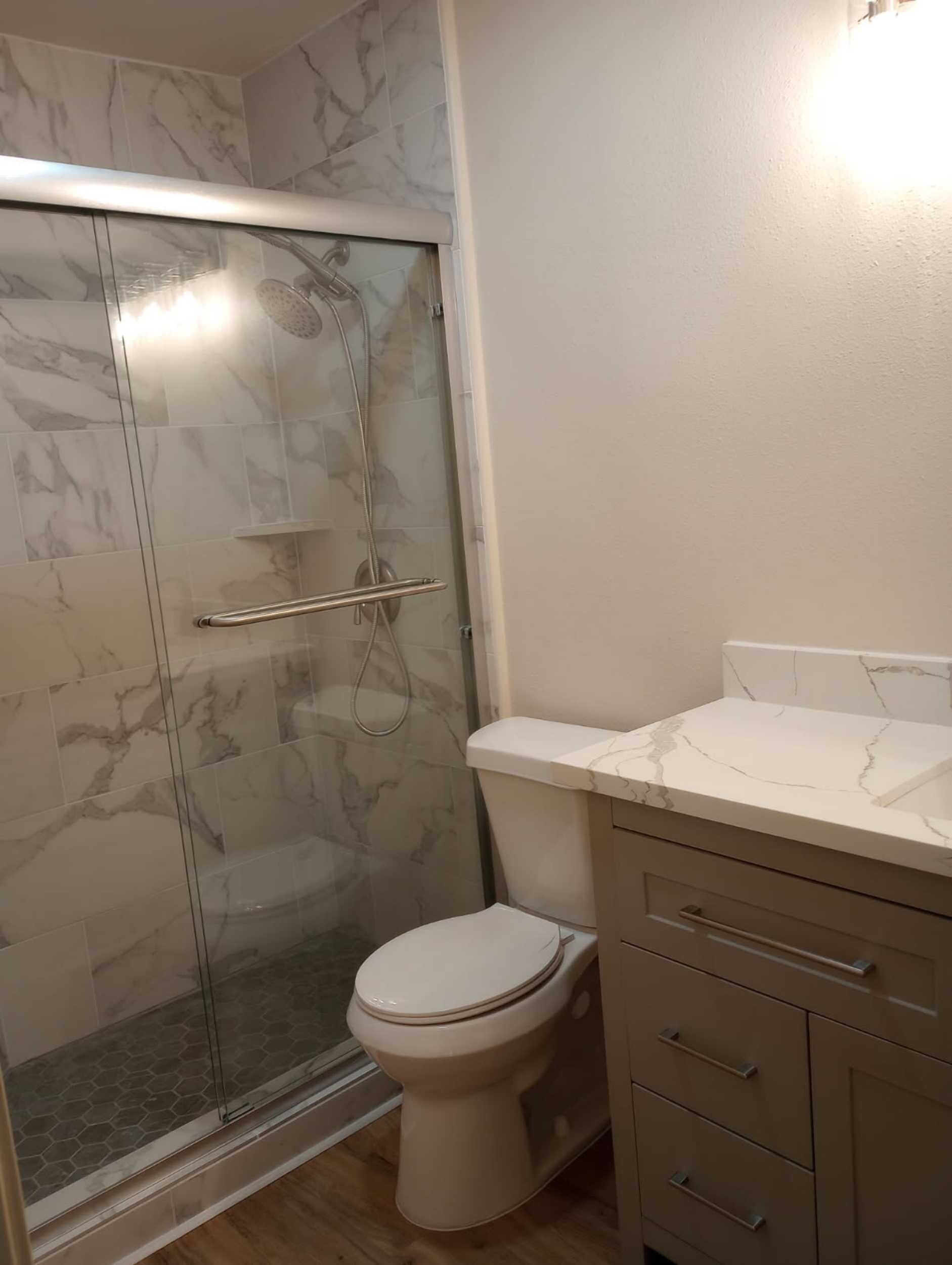 Bathroom with a glass shower, toilet, and vanity with a light gray cabinet.