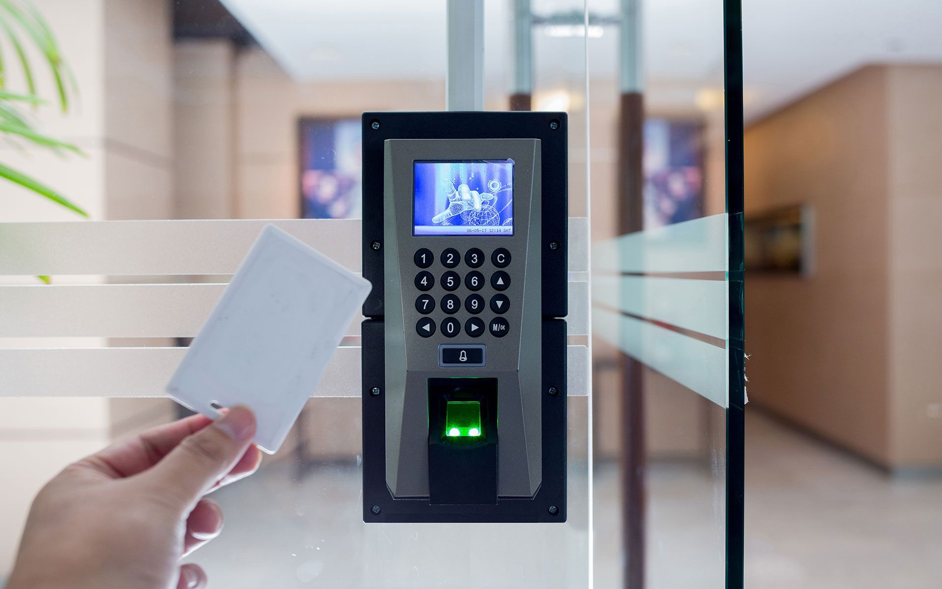 A person is holding a card in front of a fingerprint scanner.