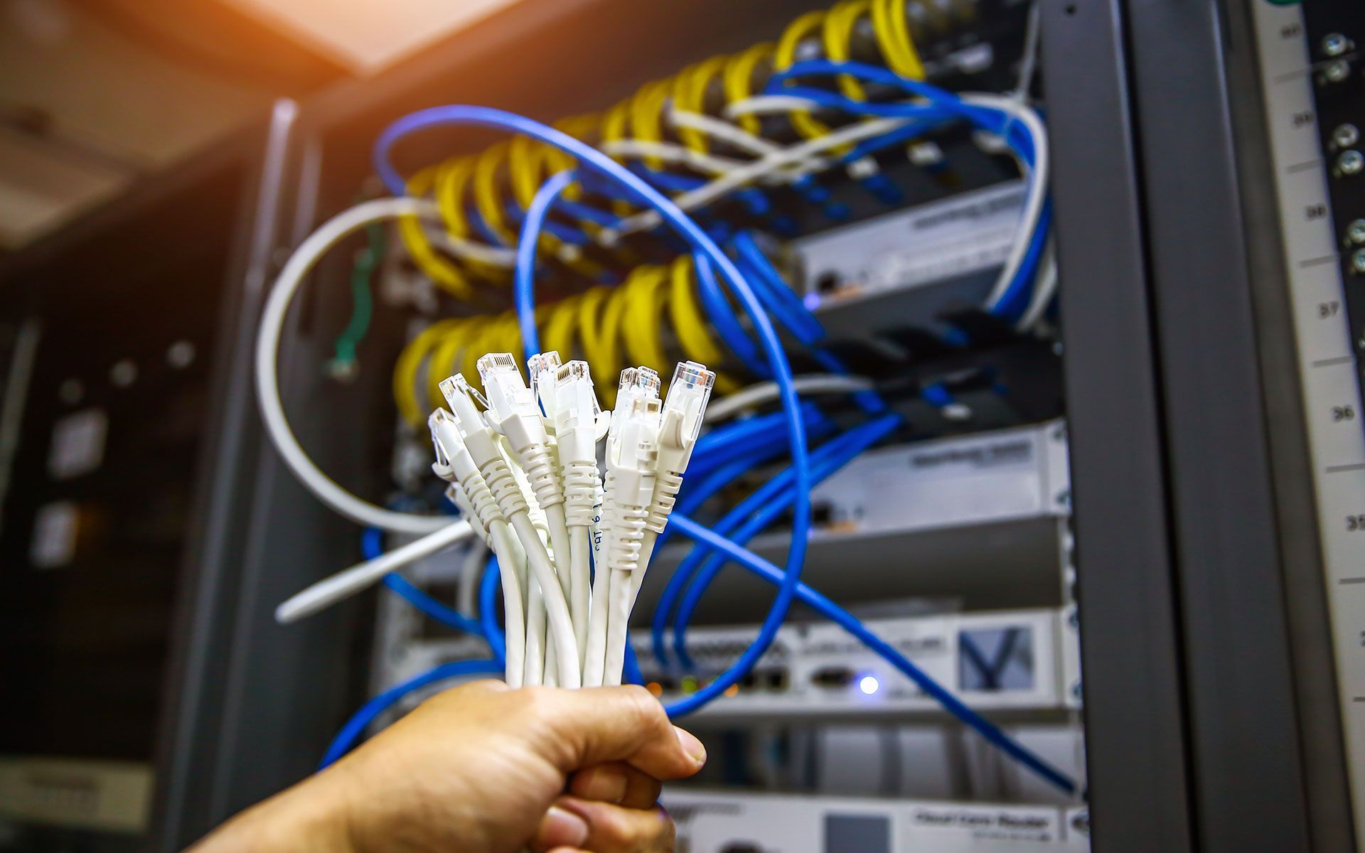 A person is holding a bunch of wires in front of a server.