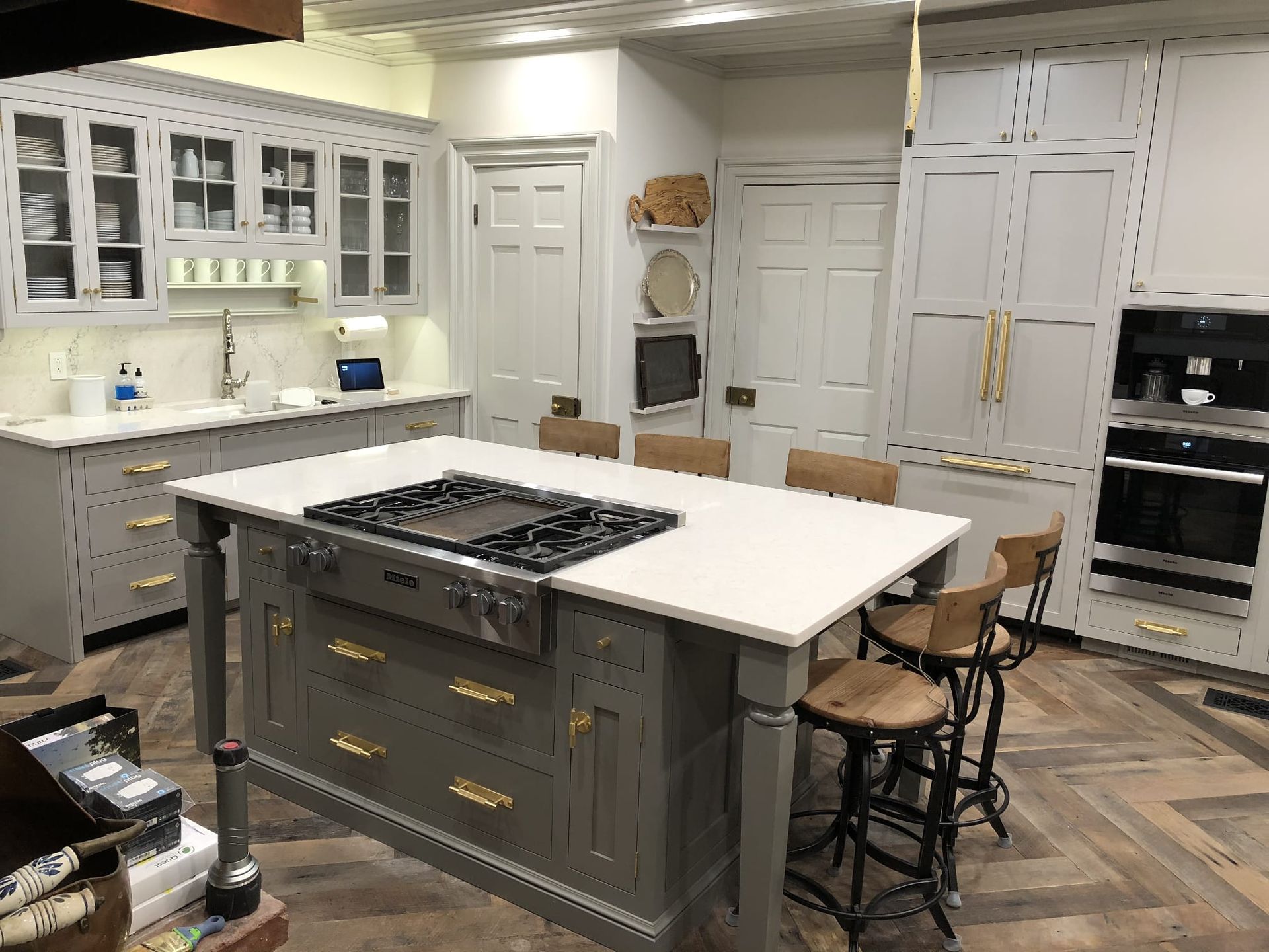 Bright white and gray kitchen with a large island, stainless appliances, and herringbone wood floor.