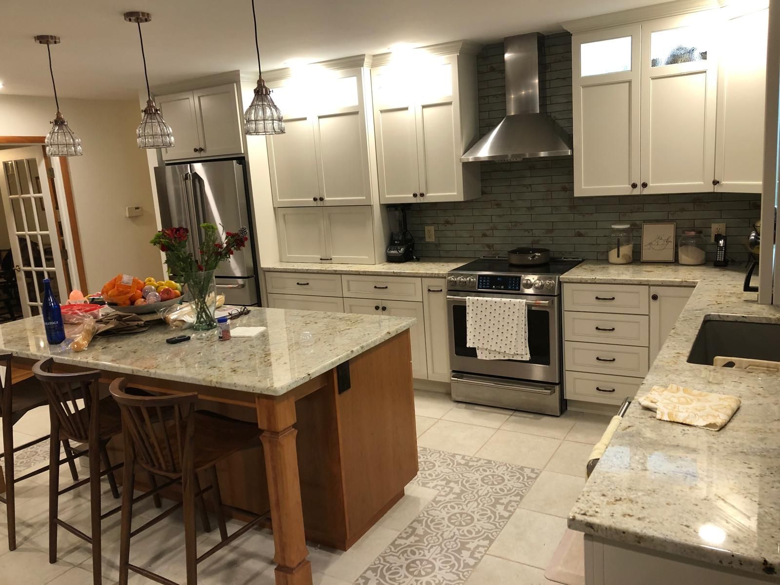 Modern kitchen with white cabinets, granite island, stainless stove, and pendant lights