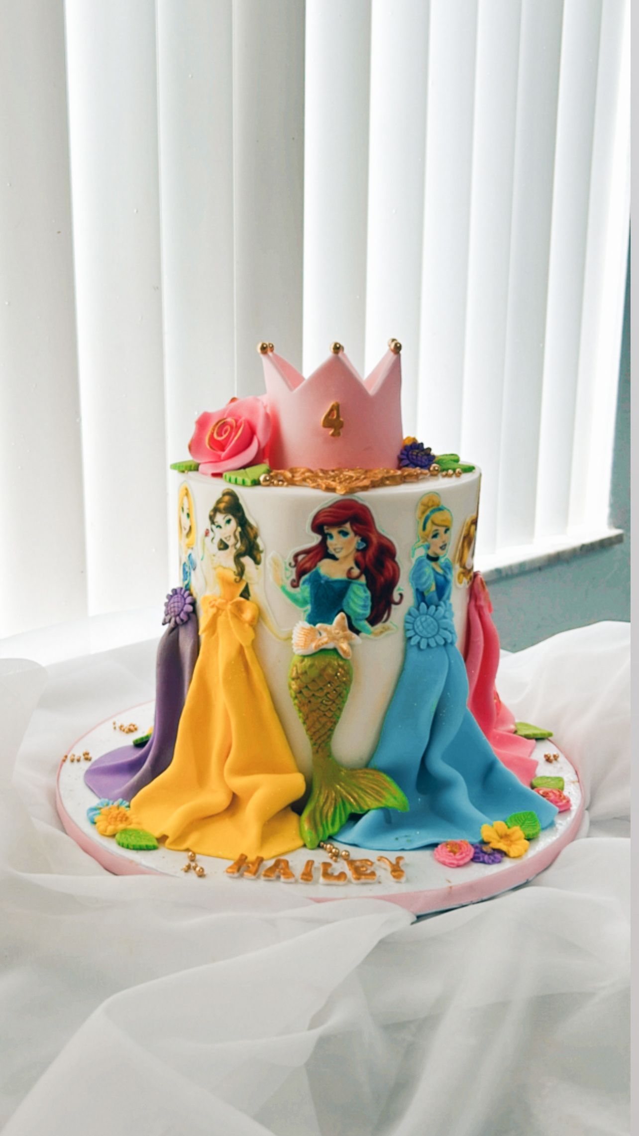 A cake with princesses on it and a crown on top.