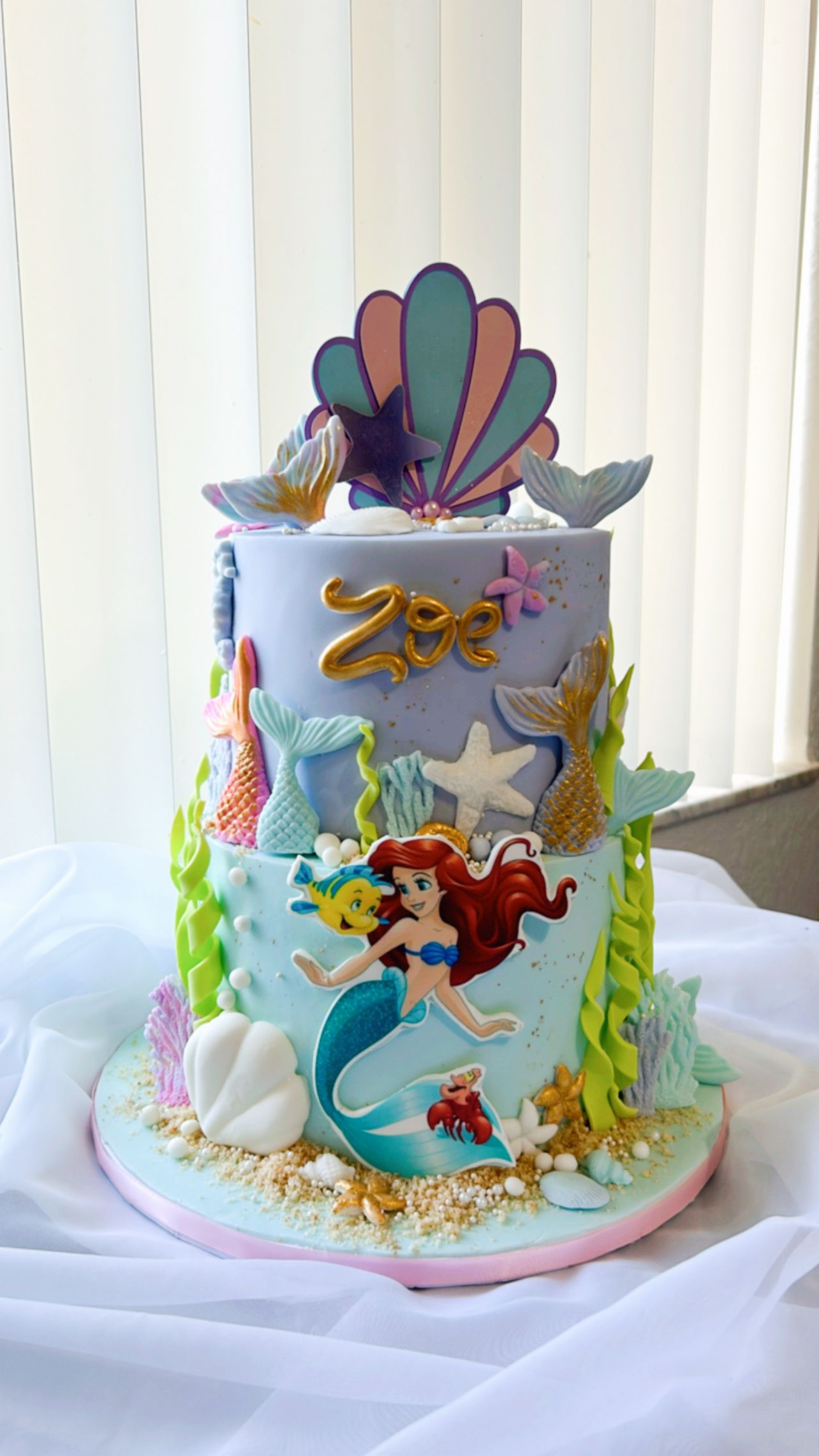A cake with a mermaid on it is sitting on a table.