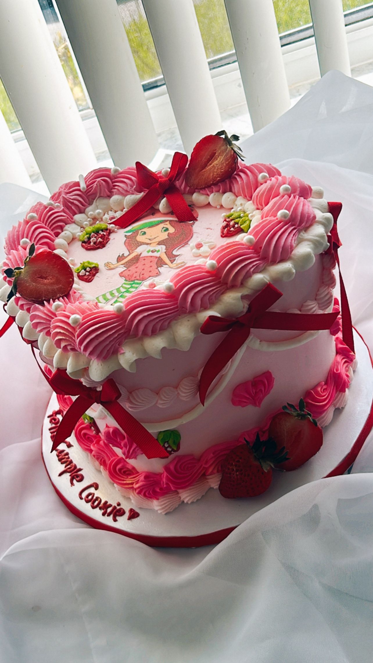 A heart shaped cake with strawberries on it is sitting on a table.