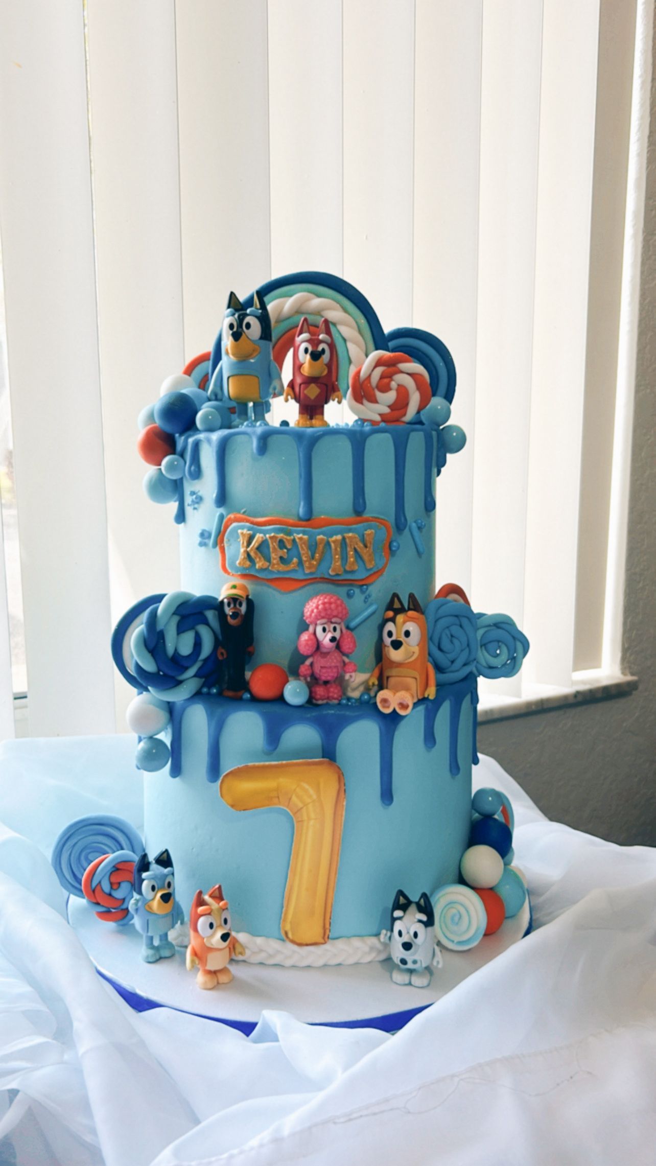 A blue cake with a number 7 on top of it is sitting on a table.