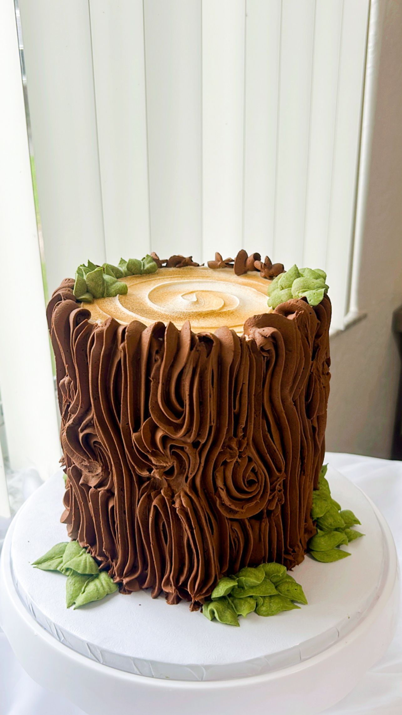 A cake decorated to look like a tree stump is sitting on a table.