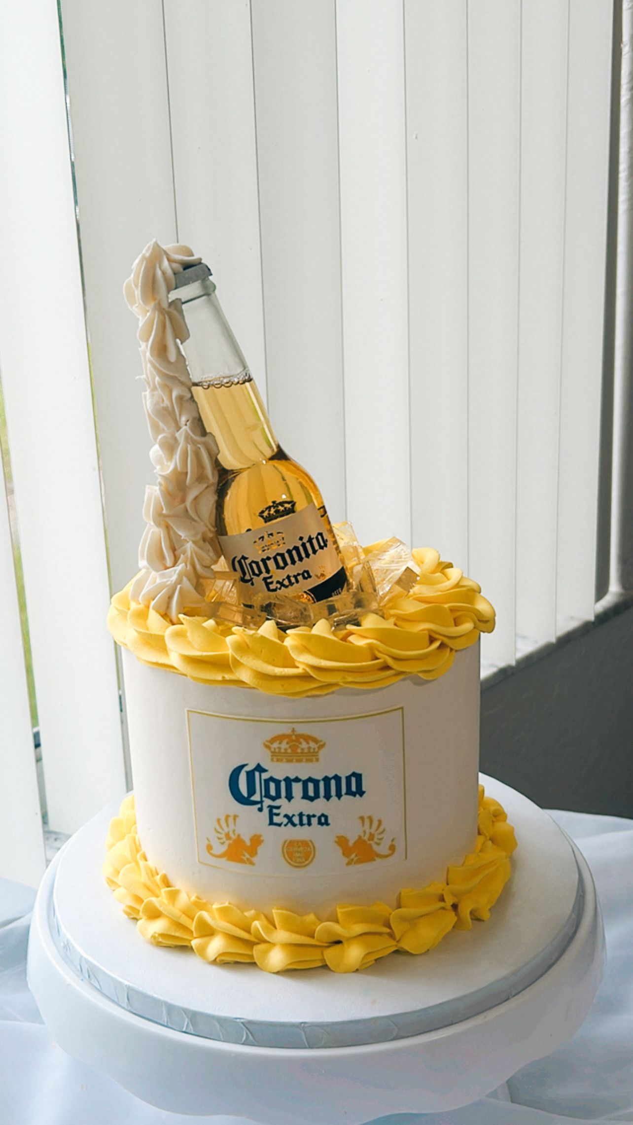 A cake with a bottle of corona extra on top of it.