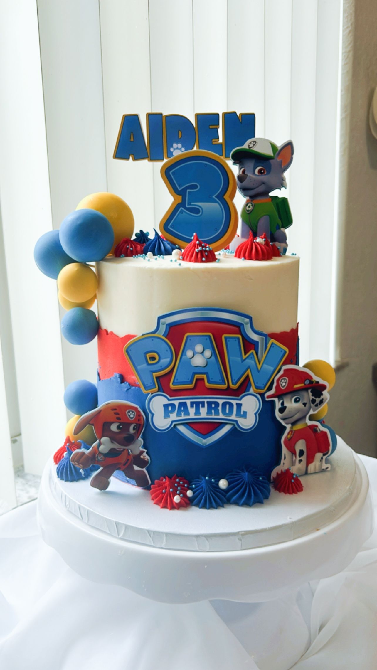 A cake with paw patrol characters on it is on a table.