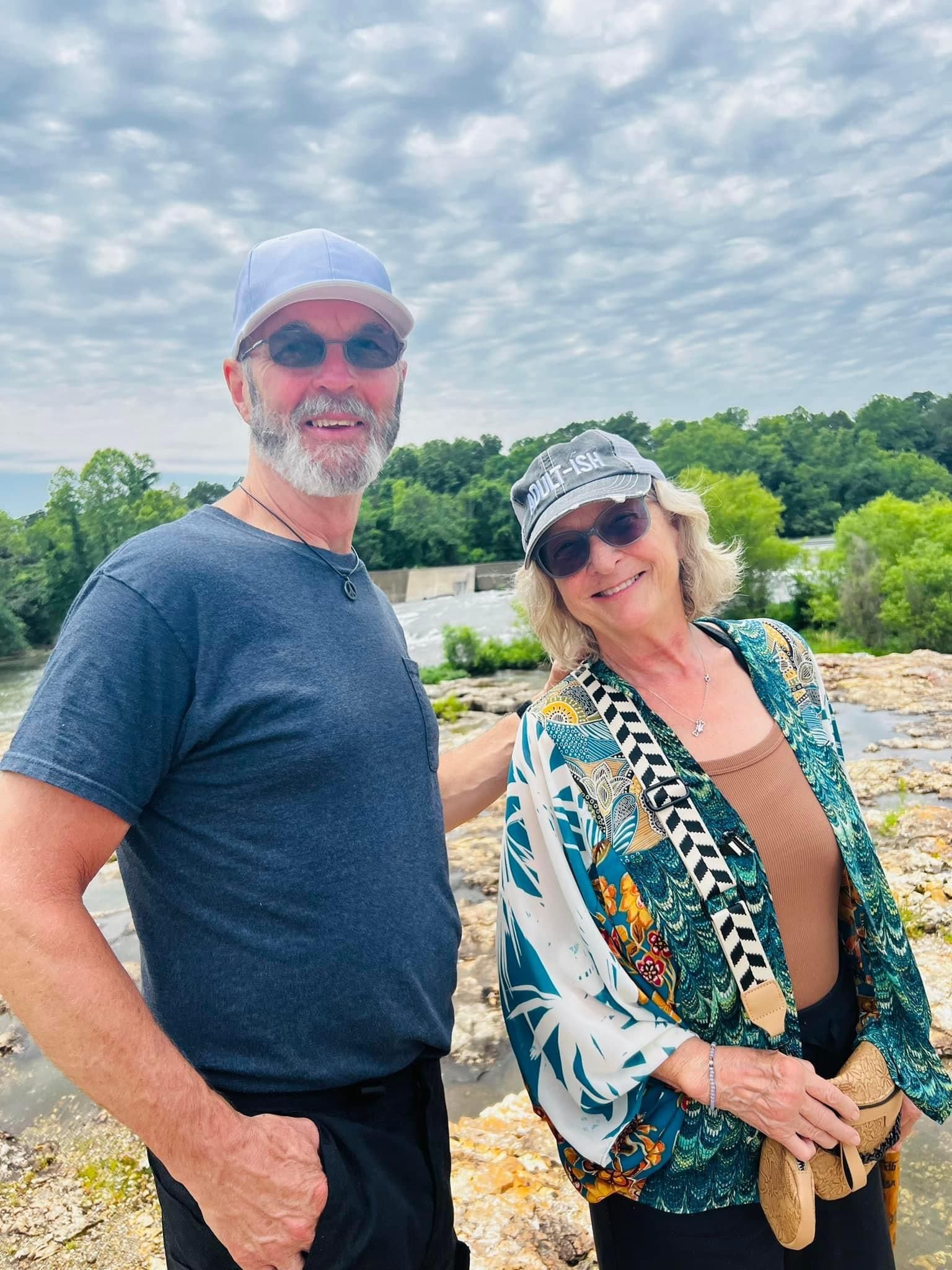 A man and a woman are standing next to each other on a rocky beach.