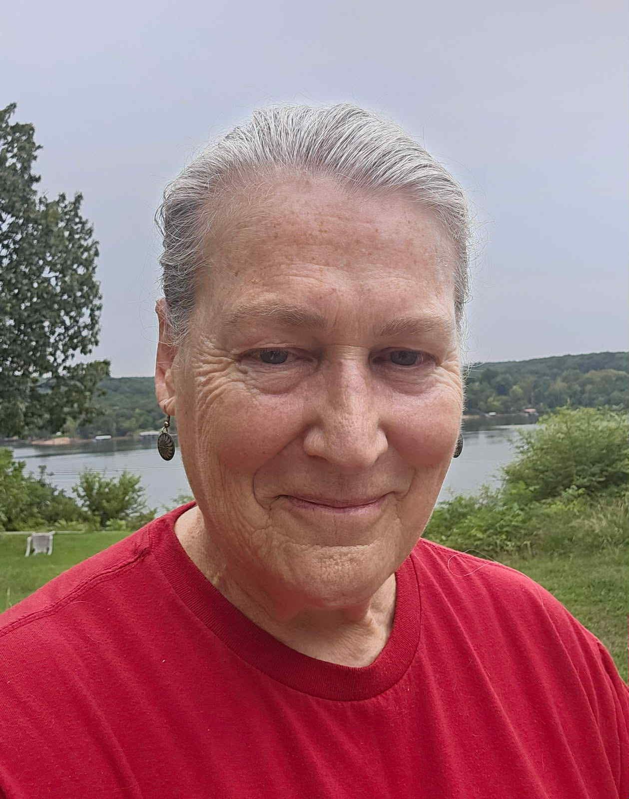 A woman in a pink tank top sits at a table with her hands folded