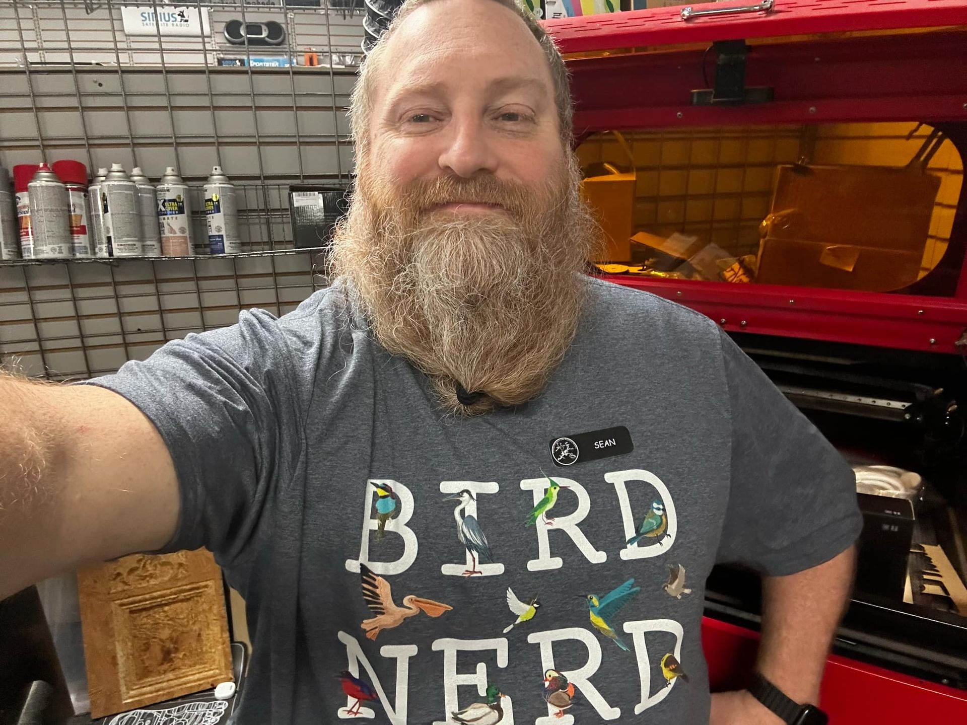 A man with a beard is wearing a bird nerd t-shirt.