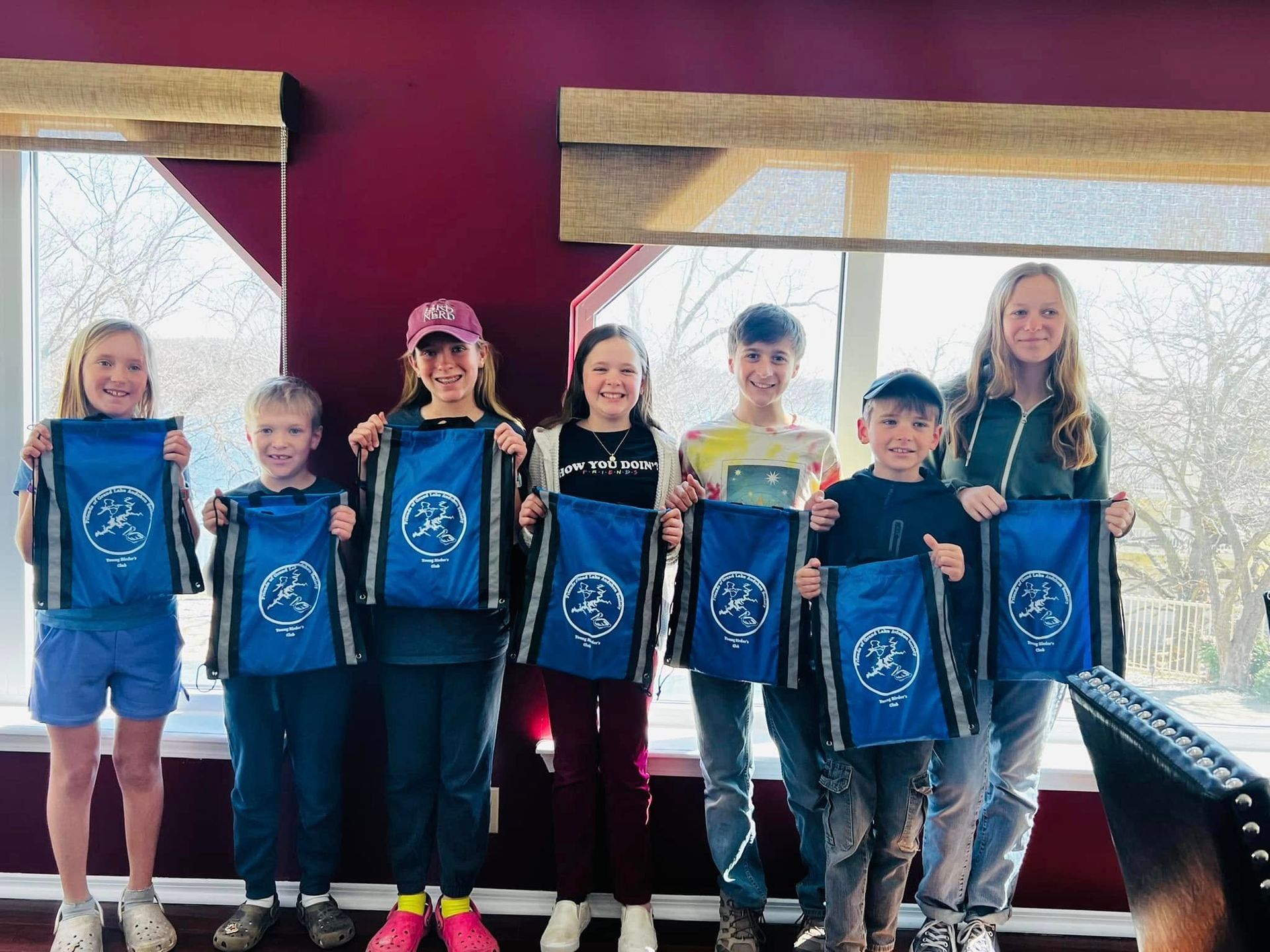 A group of children are standing next to each other holding blue bags.