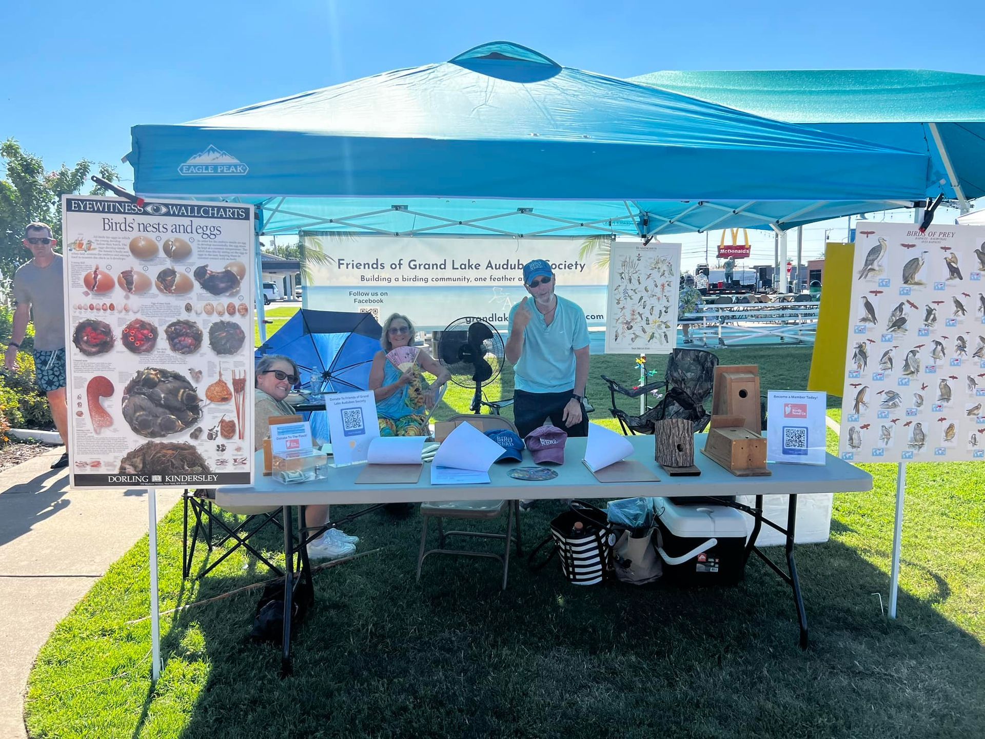 A group of people standing around a table under a tent.