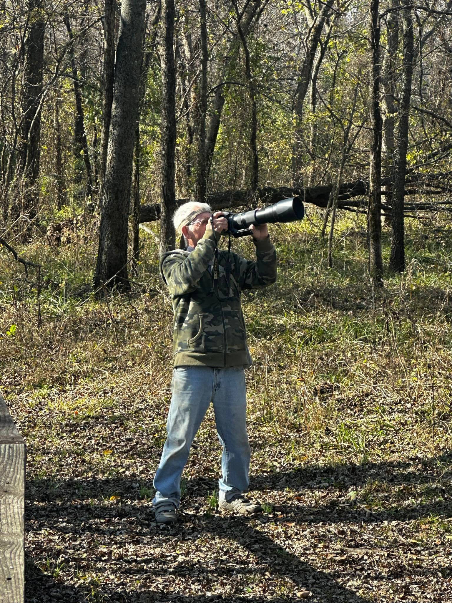 A man is standing in the woods taking a picture