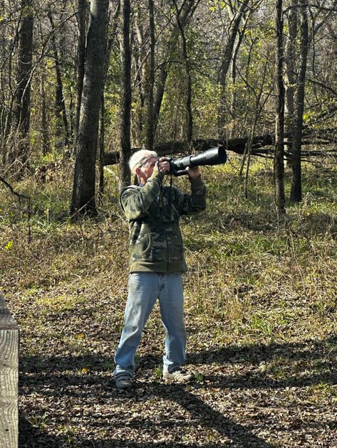 A man is standing in the woods taking a picture
