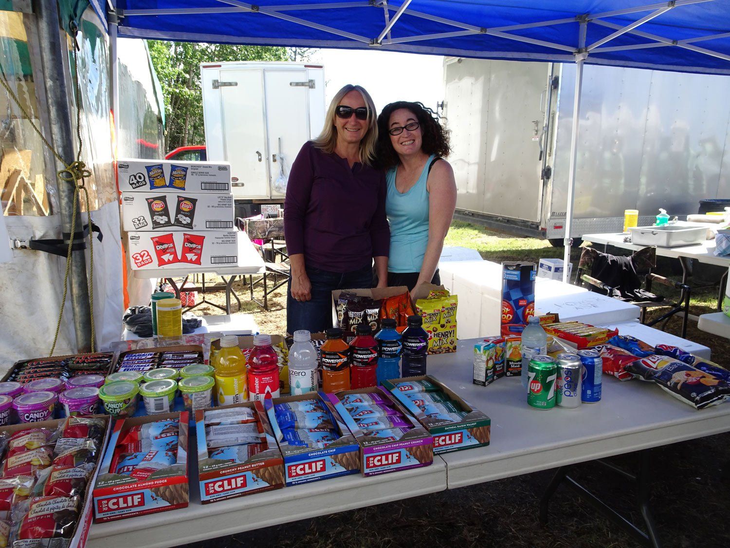 Two women are standing in front of a table full of snacks.