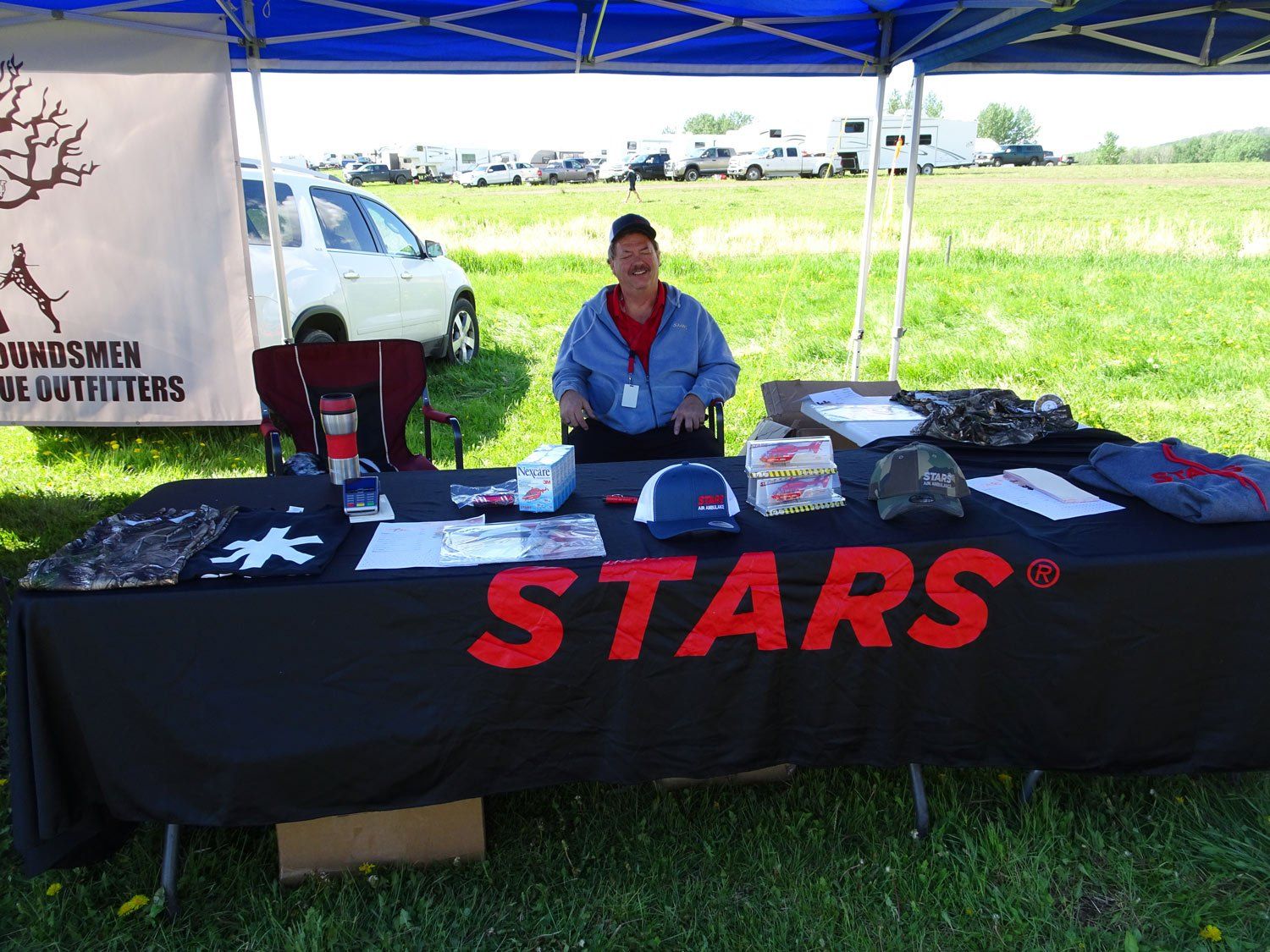 A man is sitting at a table under a tent that says stars