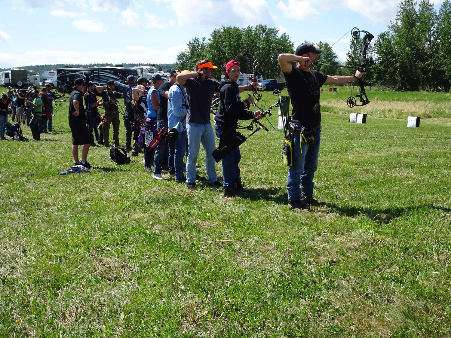 A group of people are standing in a field holding bows and arrows.