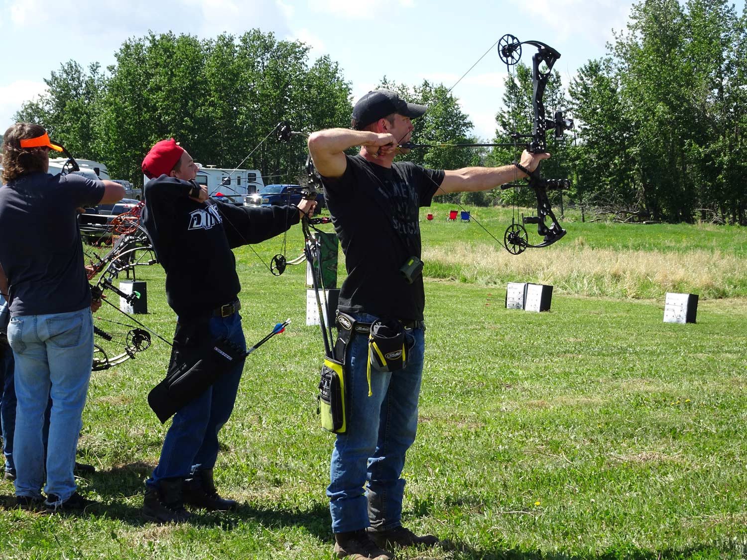 A group of people are standing in a field holding bows and arrows.