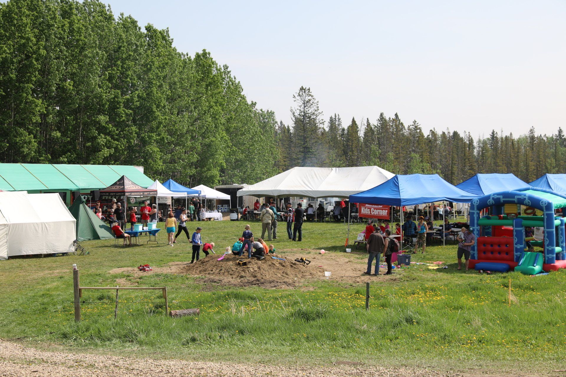 A group of people are standing in a field with tents and a bouncy house.