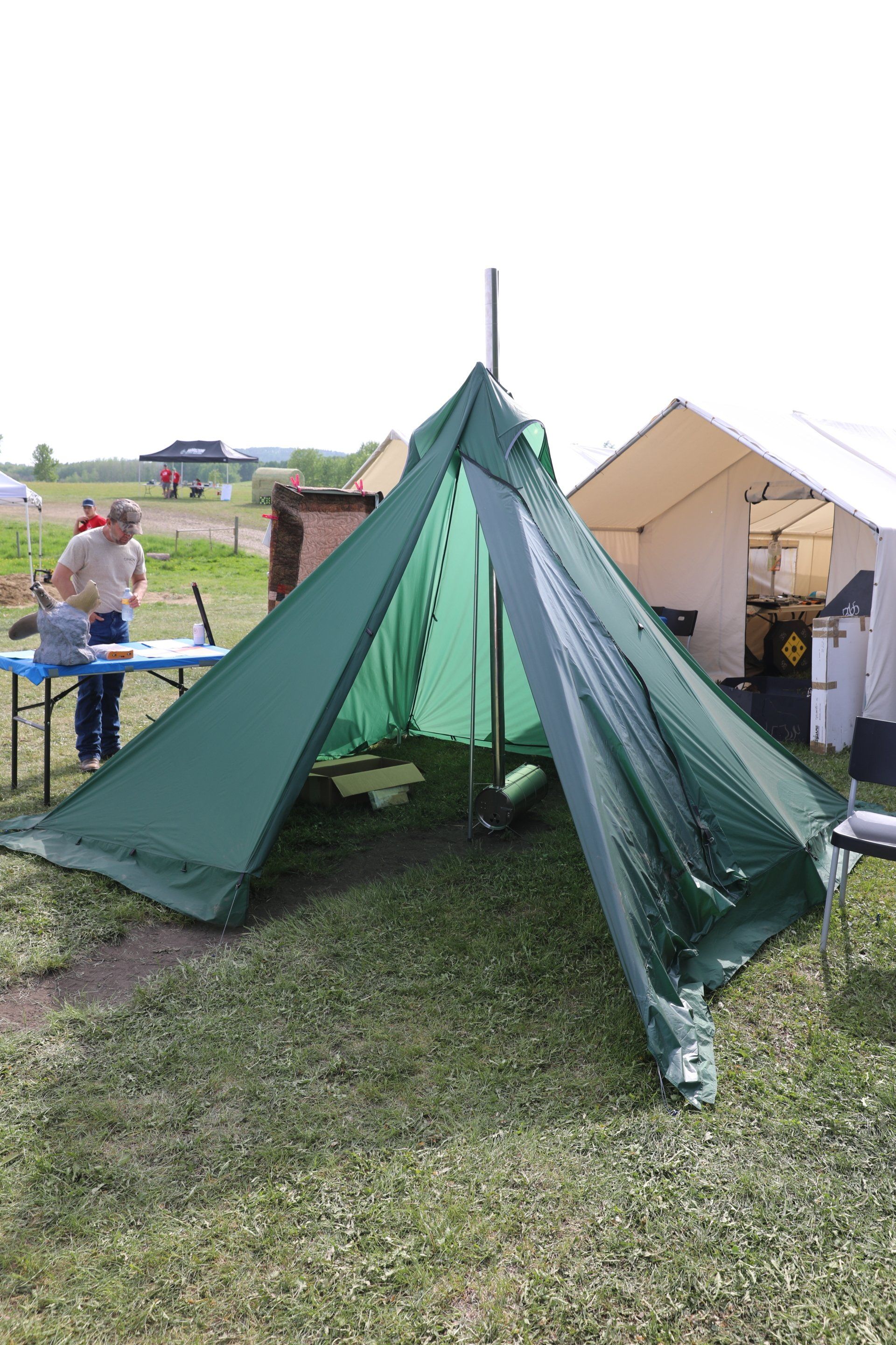 A green tent is sitting in the middle of a grassy field.