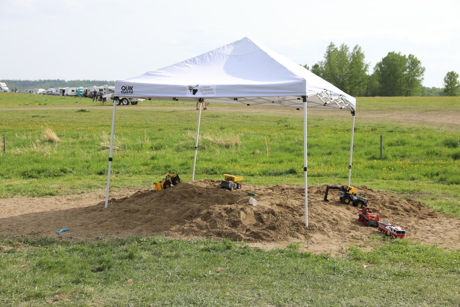 A white tent is sitting in the middle of a grassy field.