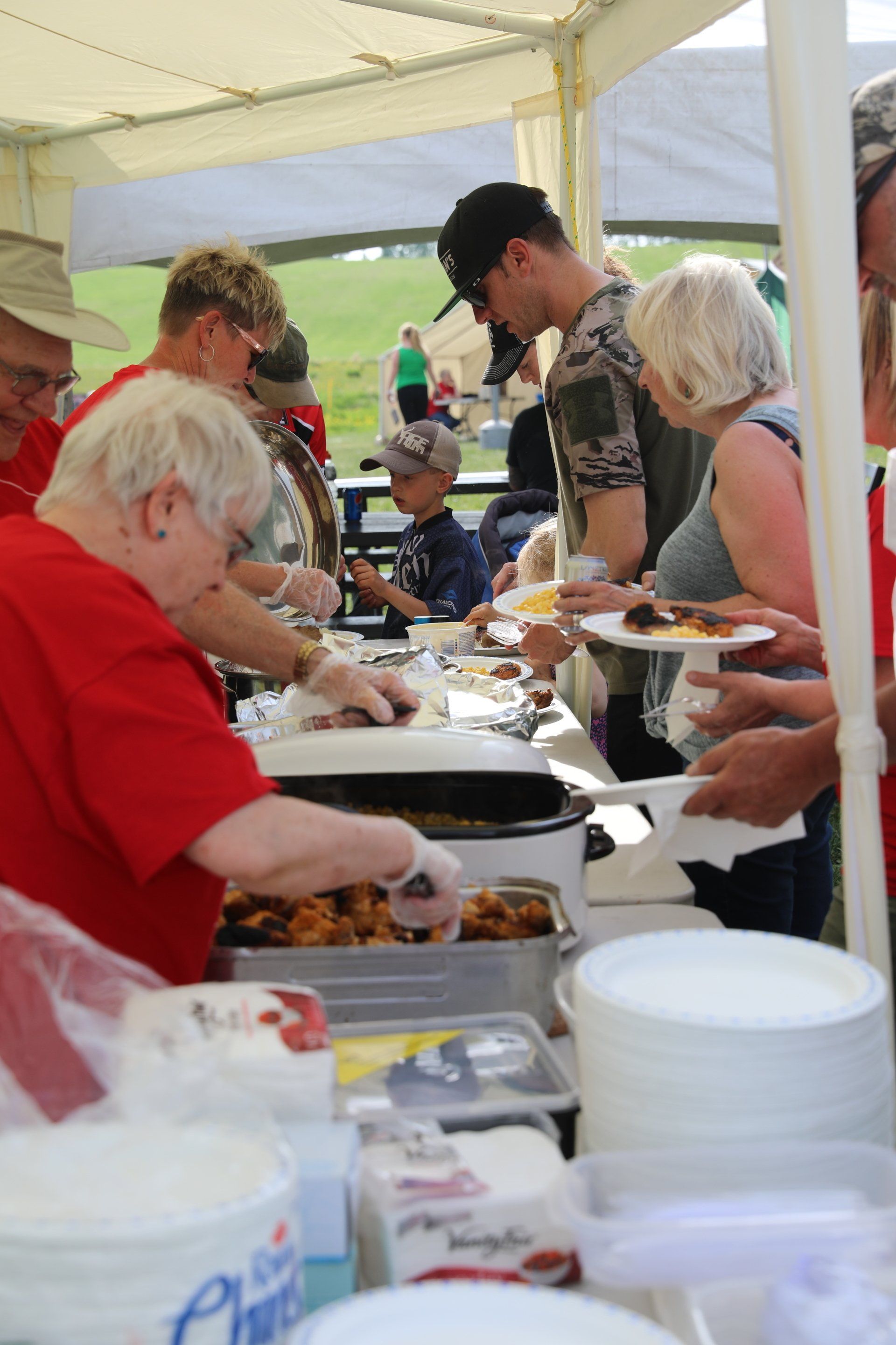 A group of people are standing around a table eating food