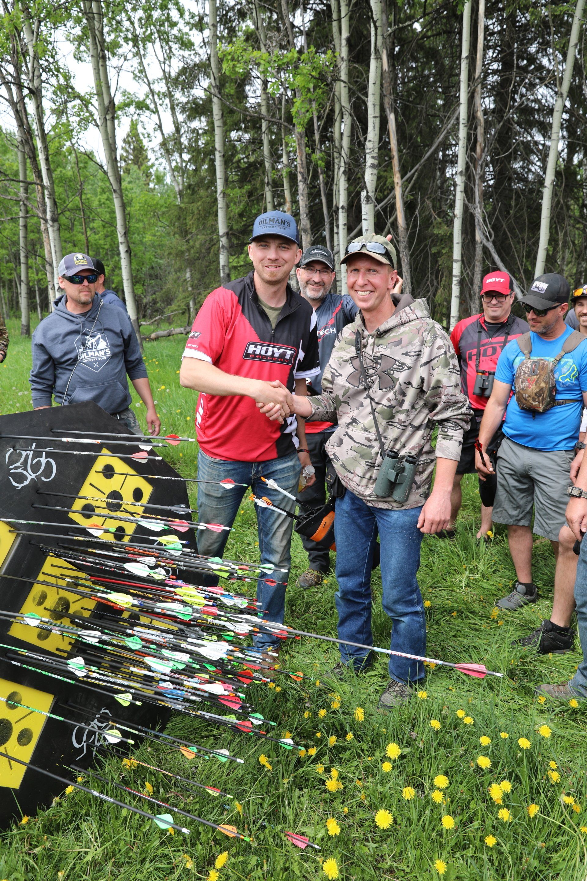A group of men are standing in a field holding bows and arrows.