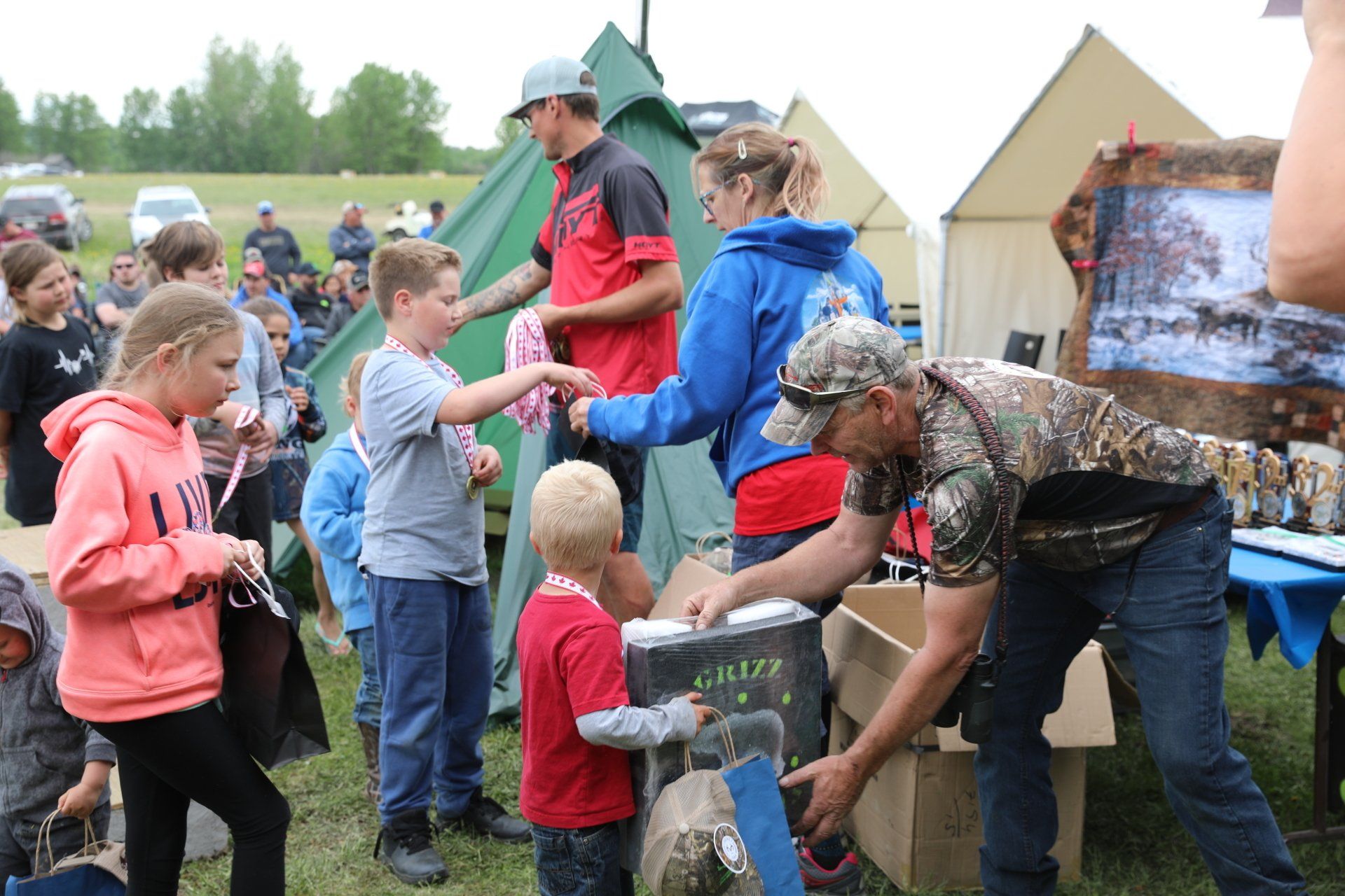 A group of people are standing around a table in a field.