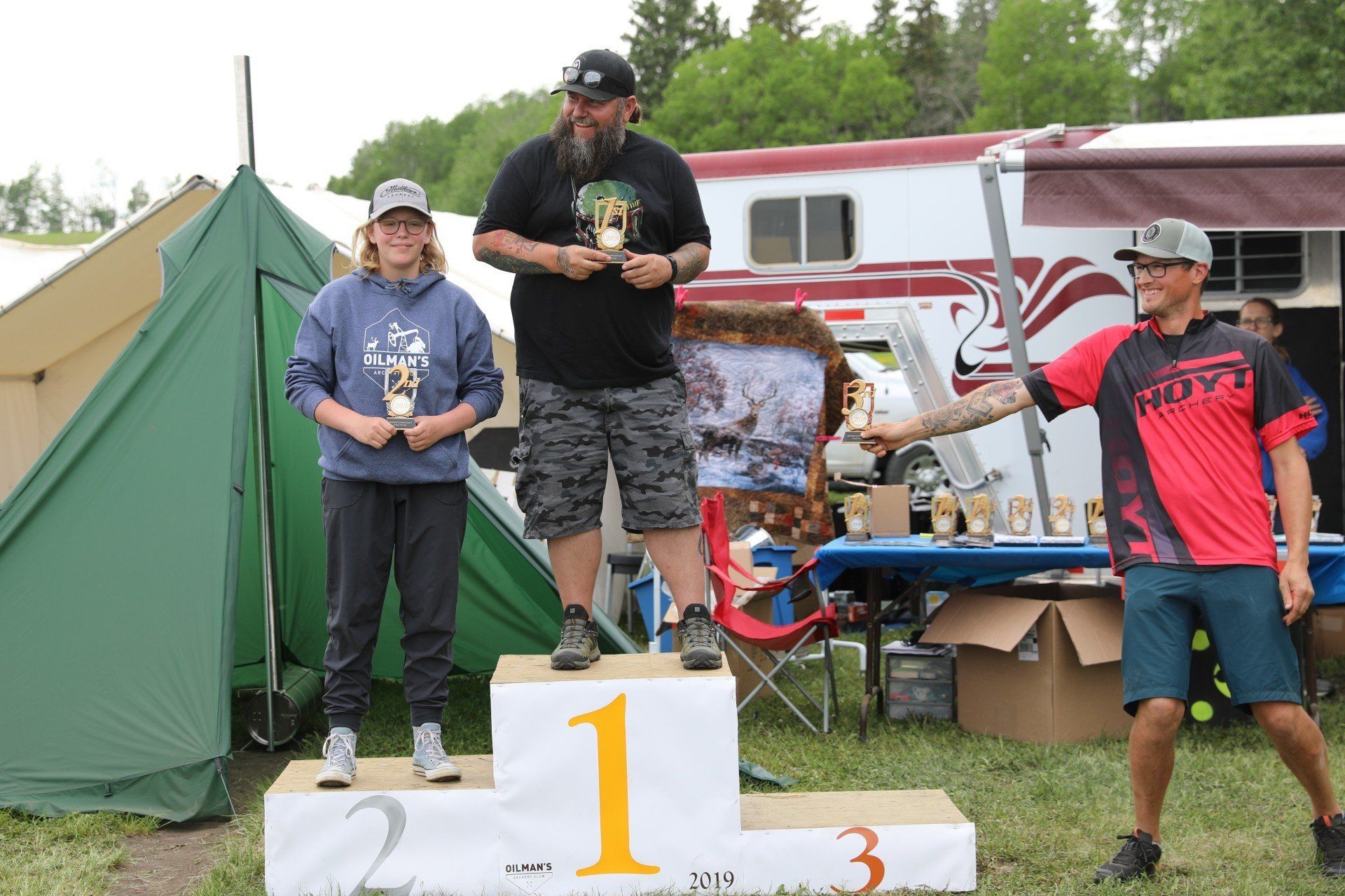 Three people are standing on a podium with the number 1 on it.