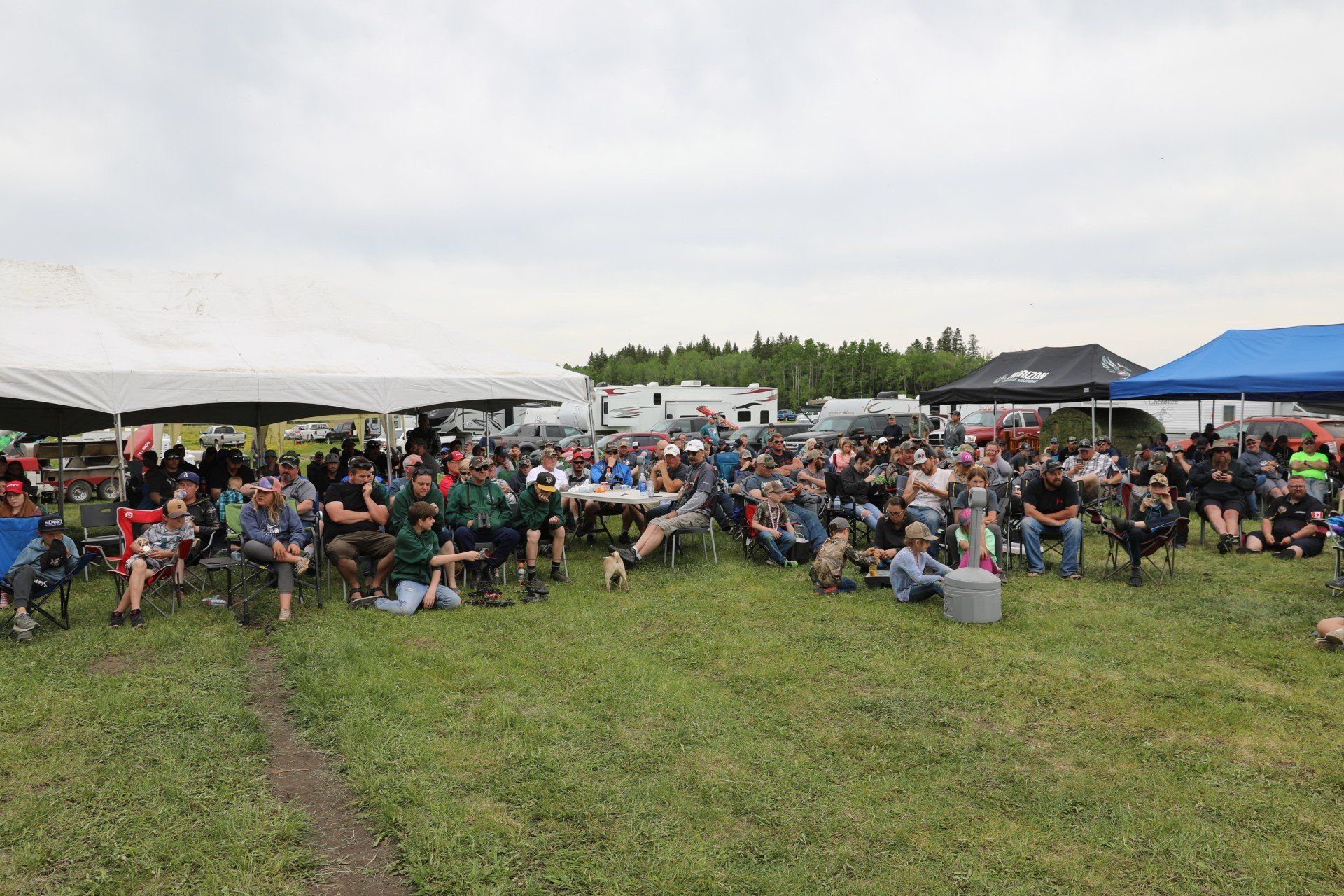 A large group of people are sitting in a grassy field.