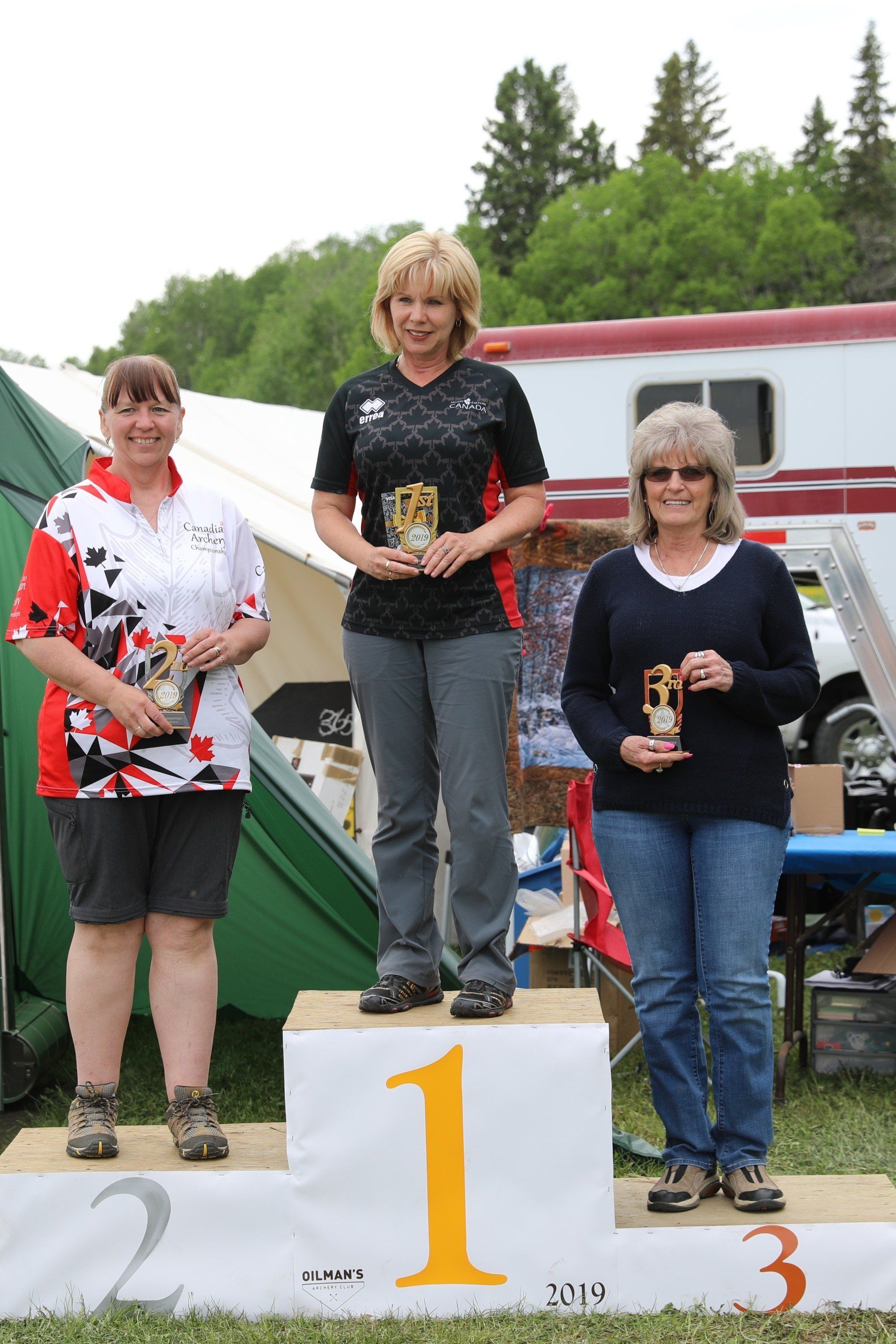 Three women stand on a podium with the number 1 on it