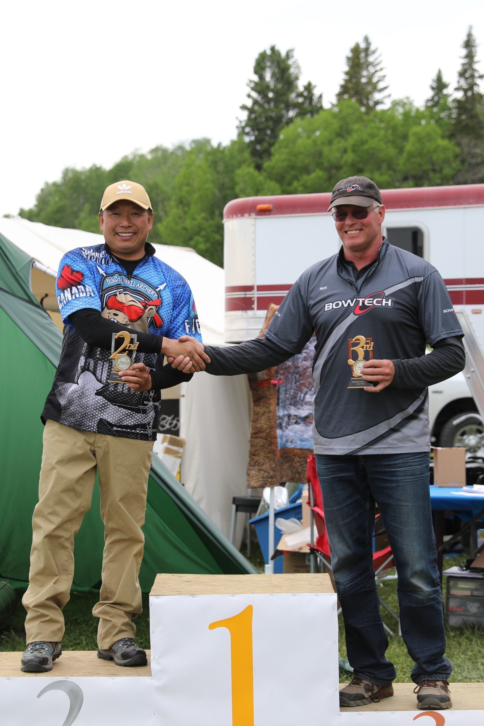 Two men shaking hands on a podium with the number 1 on it