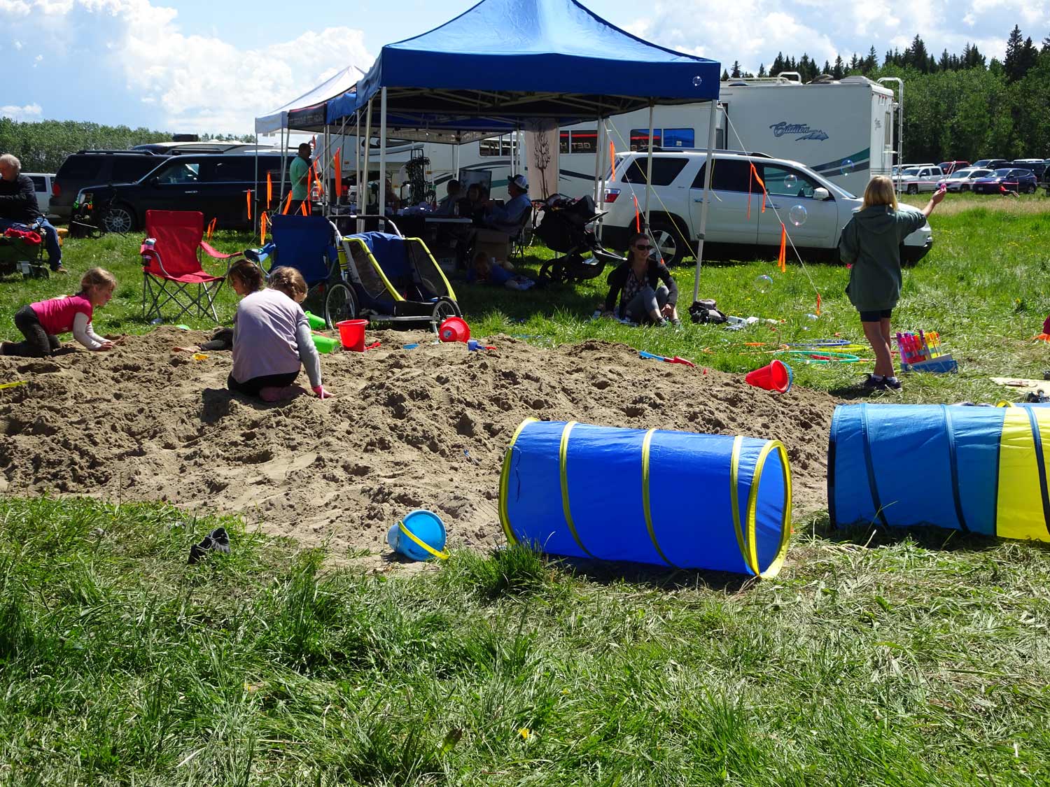 A group of children are playing in a sandbox in a field.