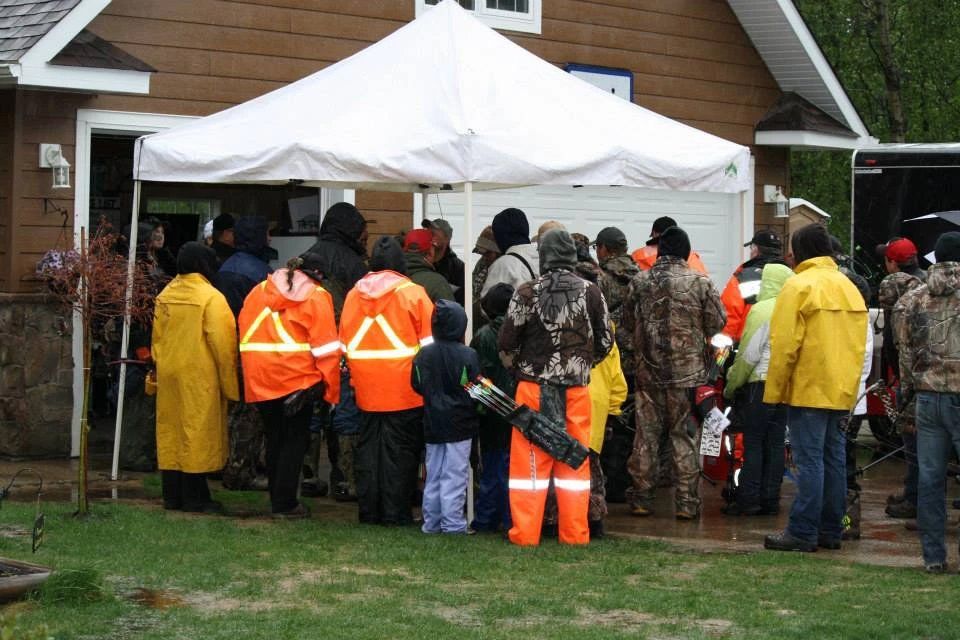 A group of people standing under a white tent in front of a house